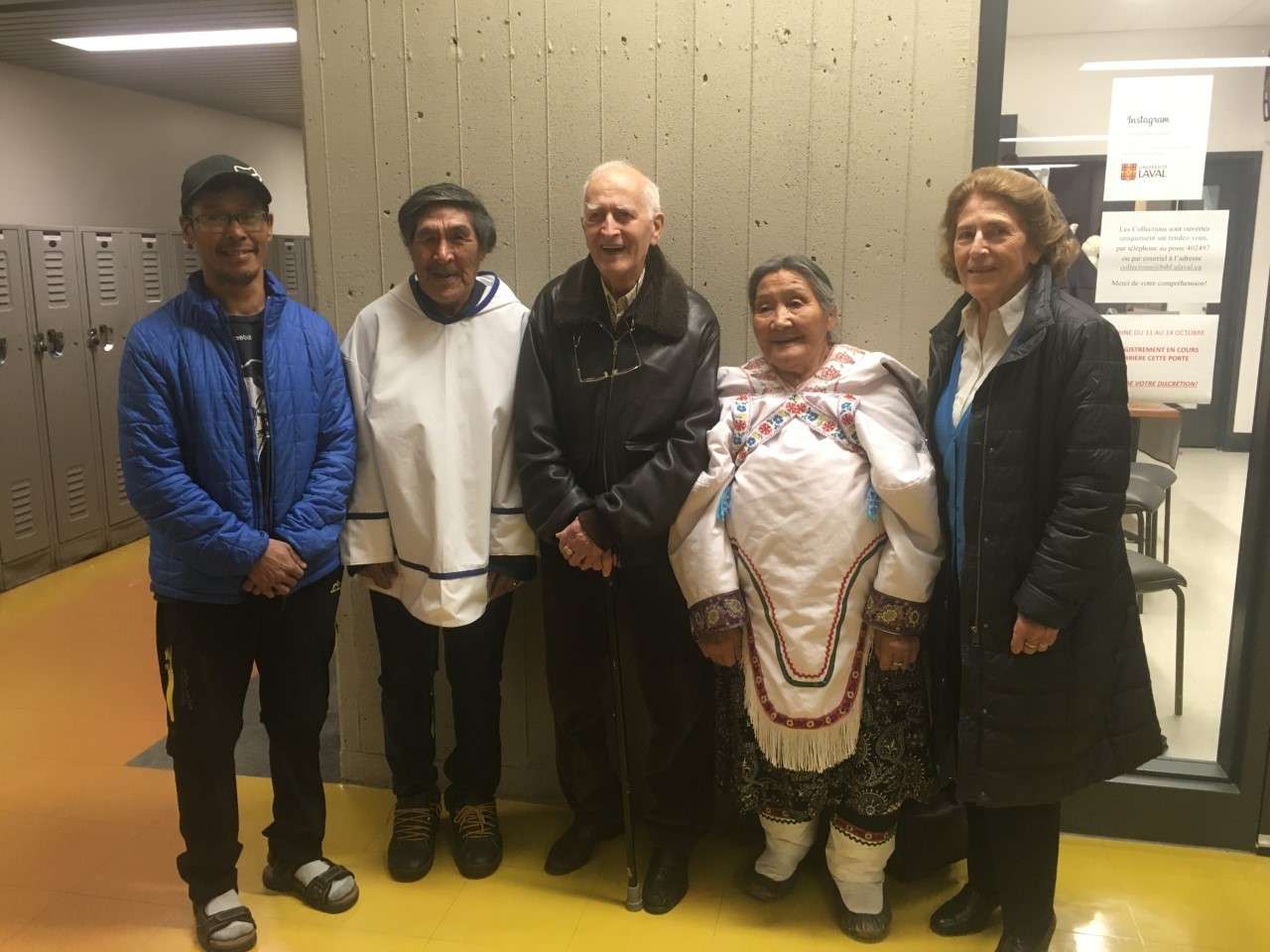Cinq personnes se tiennent debout, de face : Roland Taqtu (interprète inuk), Deborah Qaunaq et Natalino Piugattuk (deux ainés inuit), Bernard Saladin d'Anglure (qui a rassemblé cette collection d'objets) et Francoise Morin (sa conjointe).