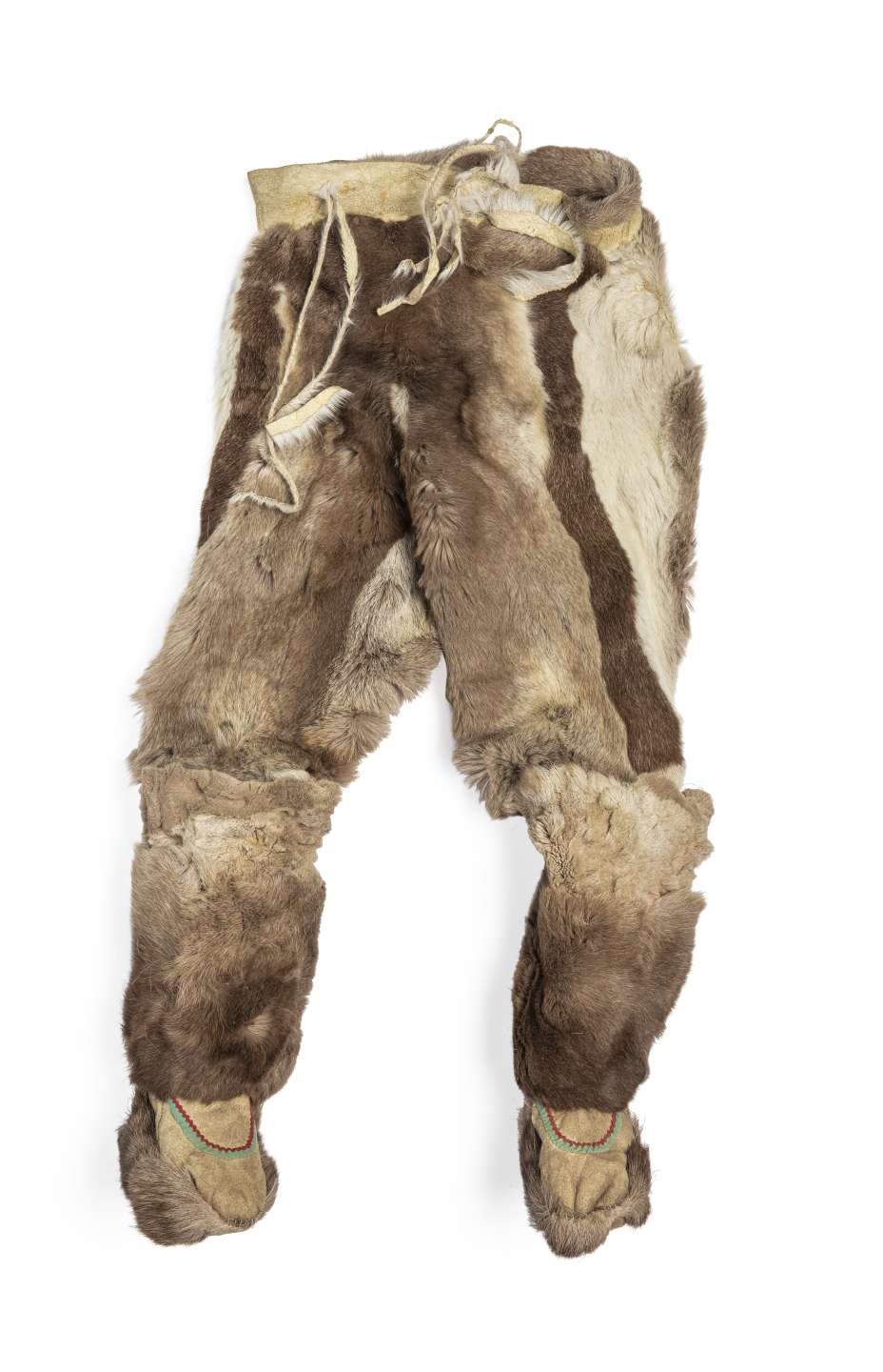 Pantalon en fourrure brune, vu de face, avec des bottes cousues &agrave; chaque jambe. Le pantalon pr&eacute;sente des bandes verticales de fourrure brune et blanche, et des cordons pendent de la taille en cuir retourn&eacute;. Les bottes, orn&eacute;es de rubans verts et rouges, sont dot&eacute;es d&rsquo;une semelle en fourrure.