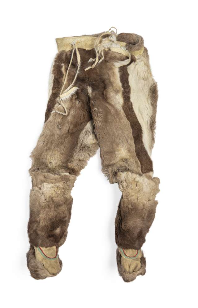 Pantalon en fourrure brune, vu de face, avec des bottes cousues &agrave; chaque jambe. Le pantalon pr&eacute;sente des bandes verticales de fourrure brune et blanche, et des cordons pendent de la taille en cuir retourn&eacute;. Les bottes, orn&eacute;es de rubans verts et rouges, sont dot&eacute;es d&rsquo;une semelle en fourrure.