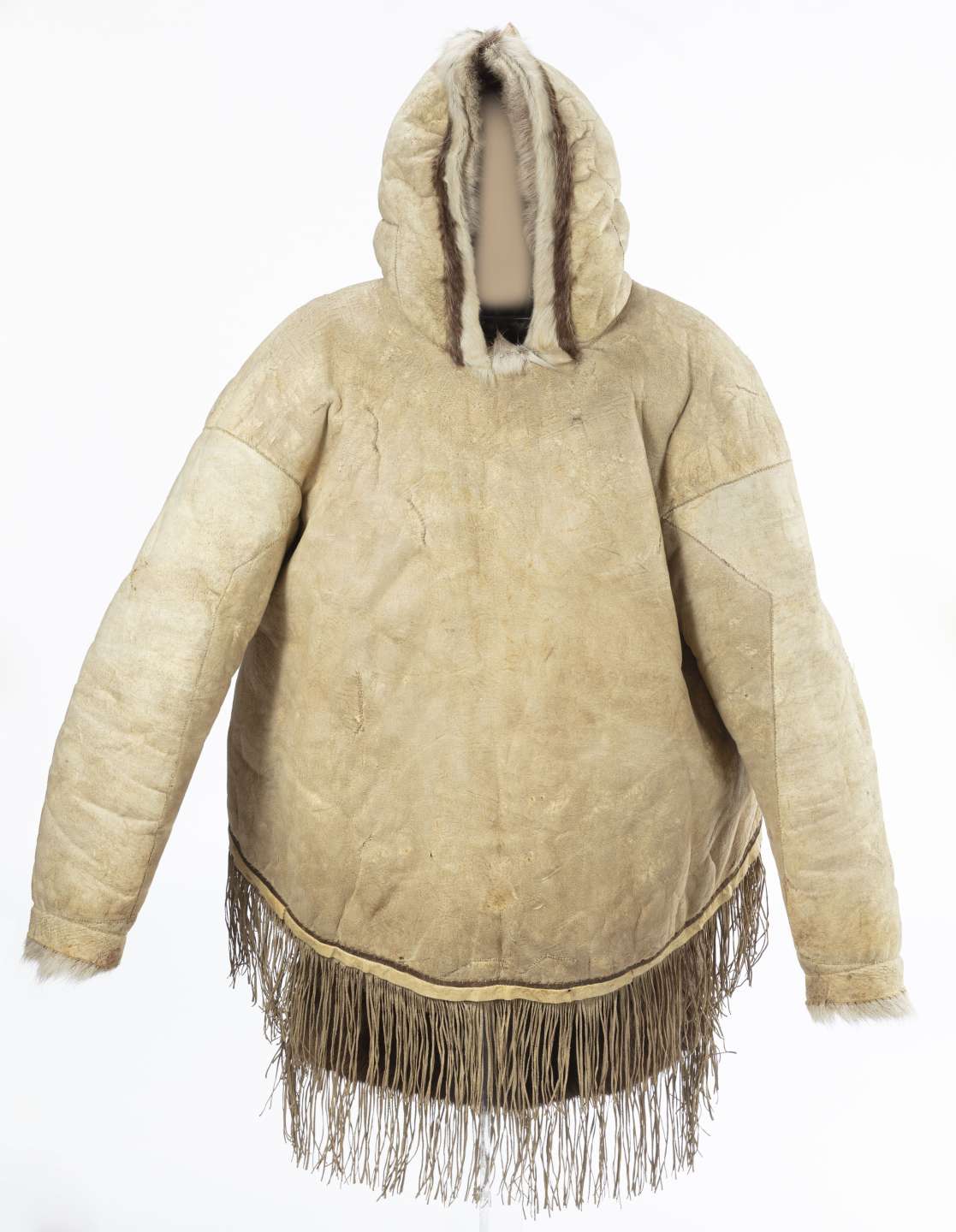 Veste en cuir beige vue de face avec le capuchon relev&eacute;. La veste est d&eacute;cor&eacute;e de franges au bas et de fourrure blanche le long de la bordure du capuchon et aux poignets.