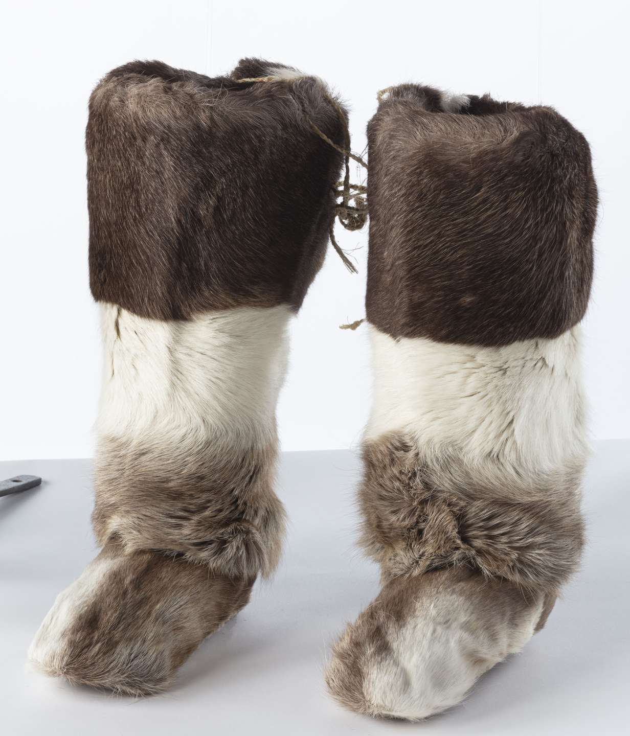 Deux bottes longues en fourrure &eacute;paisse, alternant entre brun fonc&eacute; et blanc, couvrant la totalit&eacute; des bottes.