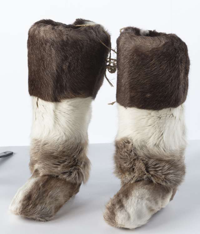 Deux bottes longues en fourrure &eacute;paisse, alternant entre brun fonc&eacute; et blanc, couvrant la totalit&eacute; des bottes.