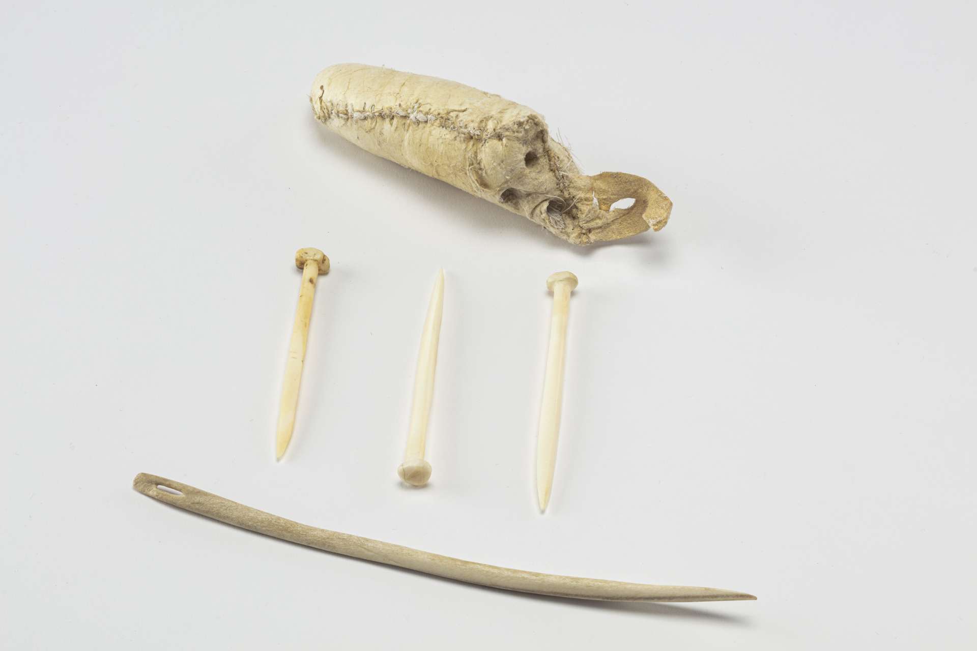 Petite trousse en cuir beige accompagn&eacute;e de trois &eacute;pingles et d&rsquo;une longue aiguille en mati&egrave;re osseuse blanche.