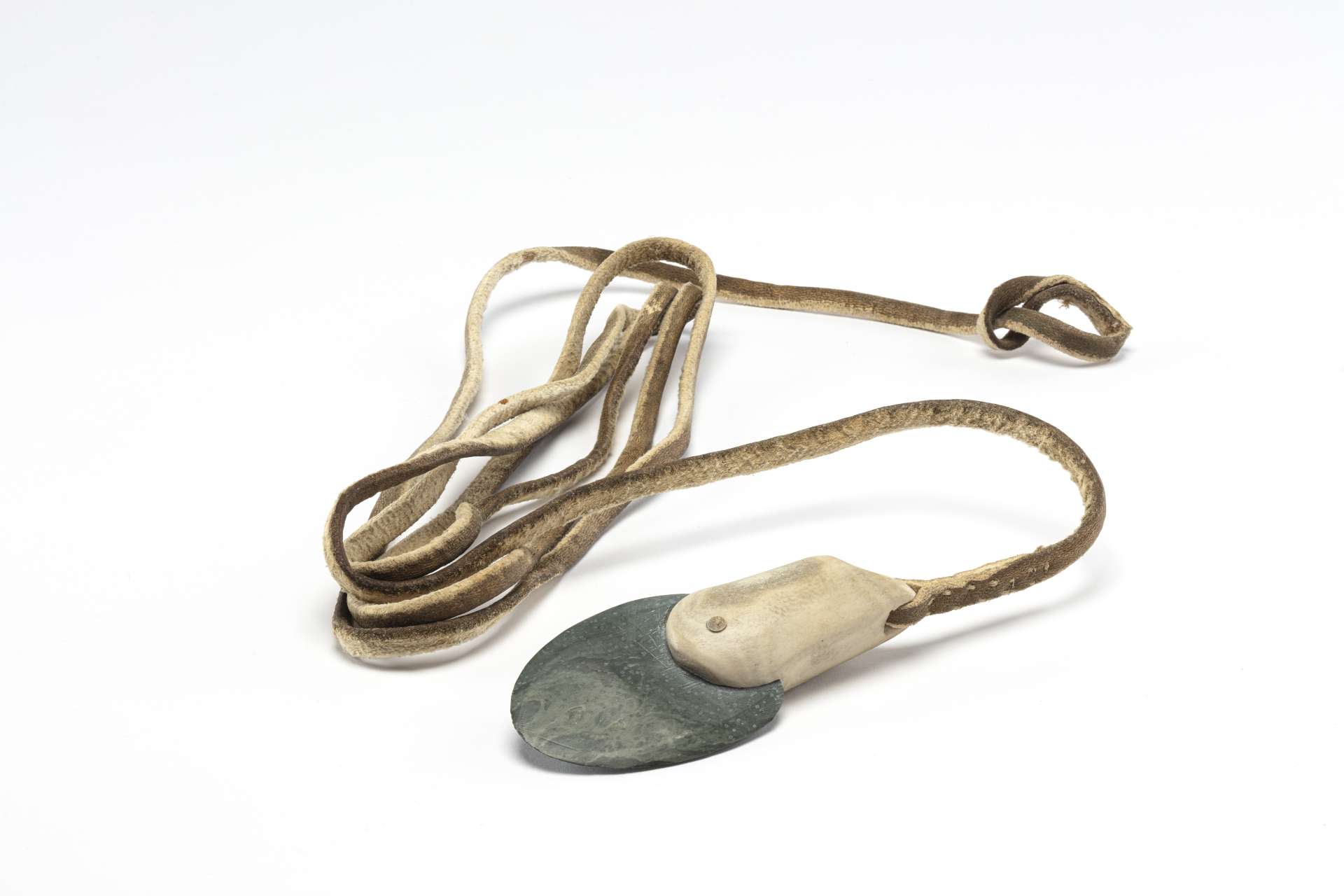 Un long cordon en cuir enroul&eacute; avec, &agrave; une extr&eacute;mit&eacute;, une t&ecirc;te de harpon compos&eacute;e de roche verd&acirc;tre ench&acirc;ss&eacute;e dans un manche en andouiller. L'autre extr&eacute;mit&eacute; du cordon se termine en boucle.