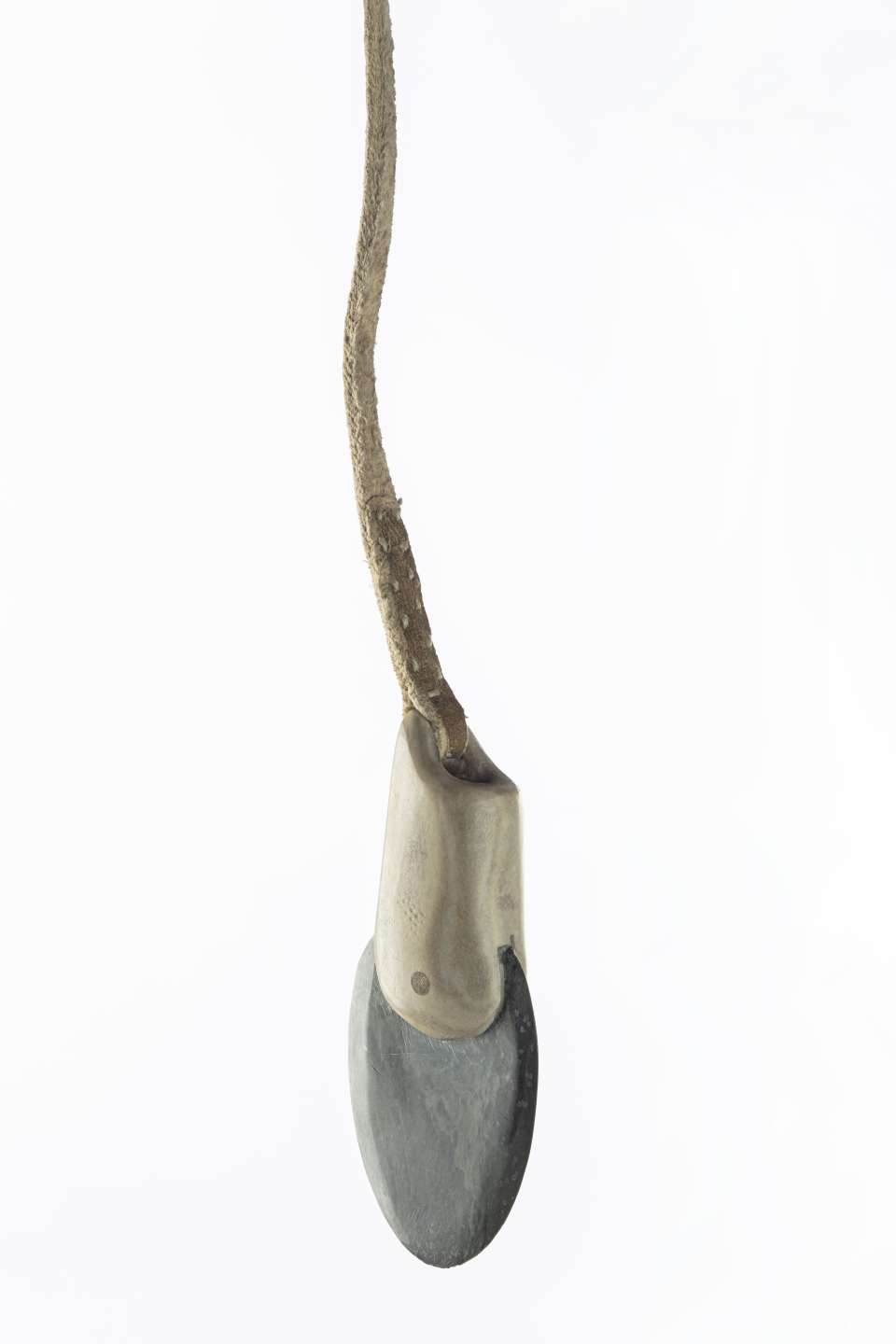 Vue rapproch&eacute;e d&rsquo;une t&ecirc;te de harpon en roche verd&acirc;tre, ench&acirc;ss&eacute;e dans un manche en andouiller attach&eacute; &agrave; un cordon en cuir. Les points de couture sur le cordon sont apparents.