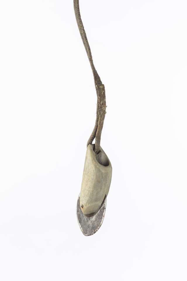 Vue rapproch&eacute;e d&rsquo;une t&ecirc;te de harpon suspendue, montrant une lame en m&eacute;tal ins&eacute;r&eacute;e dans un manche d&rsquo;andouiller attach&eacute; &agrave; un cordon en cuir. Les points de couture sur le cordon sont apparents.