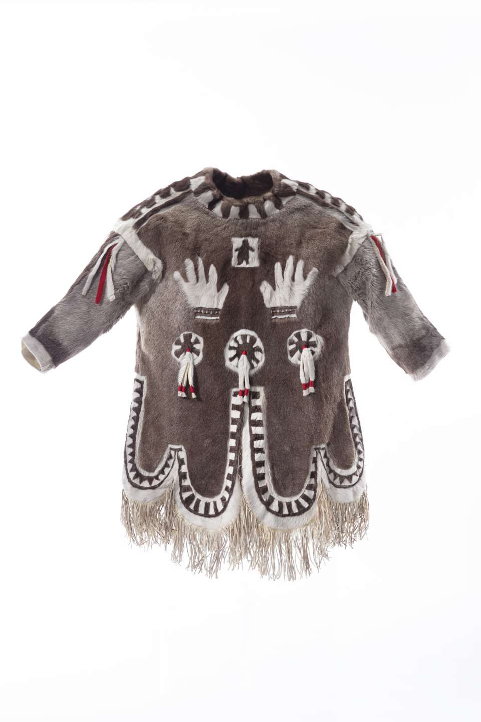 Manteau en fourrure brun orn&eacute;e de motifs blancs, vu en 360 degr&eacute;s. Sur la poitrine, deux mains blanches sont repr&eacute;sent&eacute;es sous un petit carr&eacute; central contenant une silhouette noire. Des motifs circulaires agr&eacute;ment&eacute;s de lani&egrave;re de fourrure et de tissu aux couleurs blanche et rouge sont visibles &agrave; l&rsquo;avant et &agrave; l&rsquo;arri&egrave;re du manteau. Le dos pr&eacute;sente &eacute;galement des motifs lin&eacute;aires blancs. Le bas du manteau, le col et les &eacute;paules pr&eacute;sentent des bandes de fourrure brune et blanche altern&eacute;es. Le bas du manteau est bord&eacute; de longues franges.